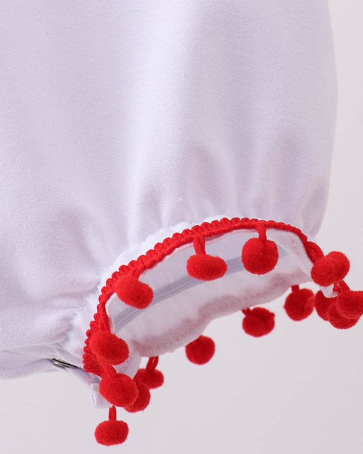 Close-up of a white garment with red pom-pom trim on a white background