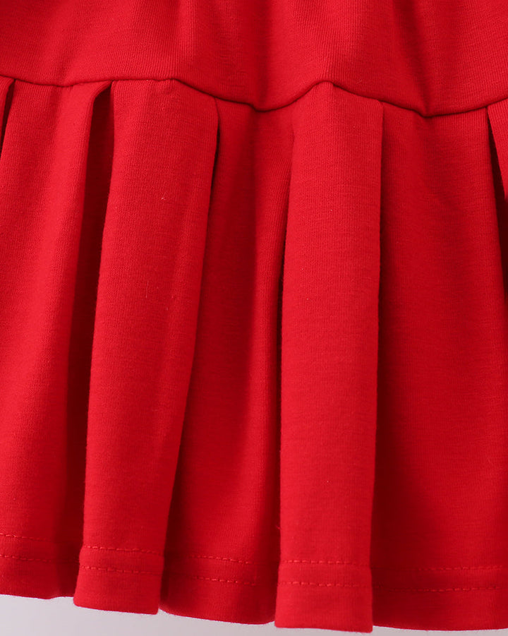 Close-up of a red pleated skirt on a light gray background