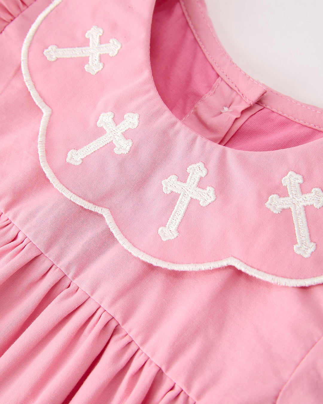 Girls pink dress with scalloped white-trim collar and small white cross embroidery