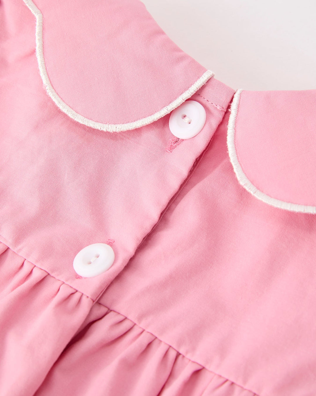 Girls pink dress bodice with white-trim collar, button placket, and gathered skirt