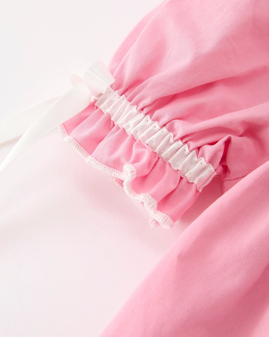 Girls pink long-sleeve dress with ruffled elastic cuff and white bow accents