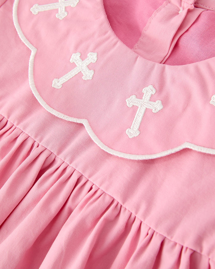 Pink christening dress bib with white embroidered crosses and scalloped white trim