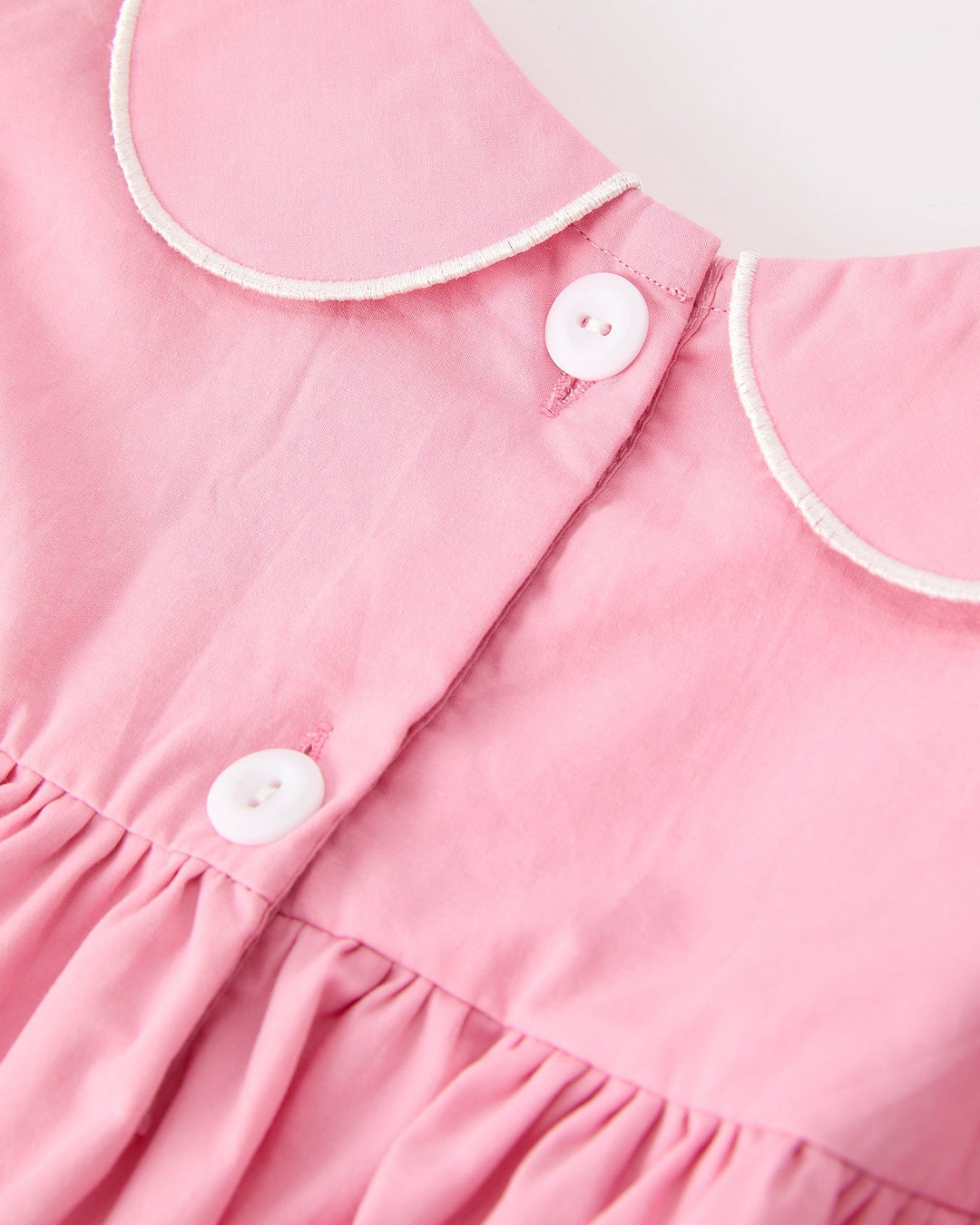 Pink christening dress with white-trimmed collar and button placket detail