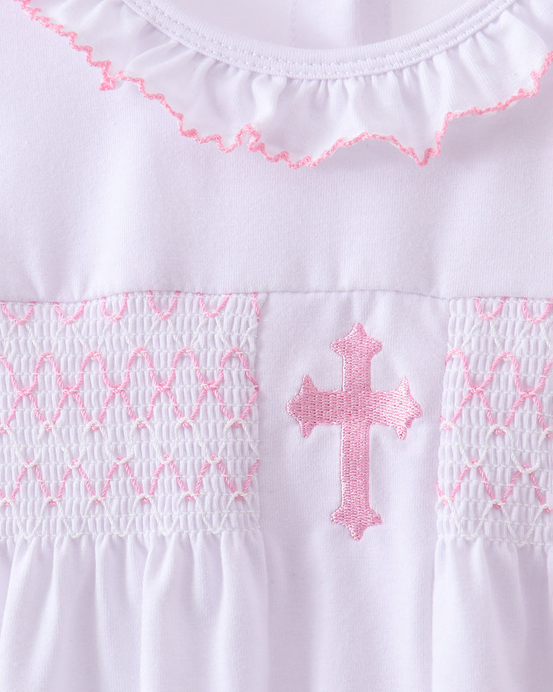 White smocked bodice with pink cross applique and pink ruffled neckline trim