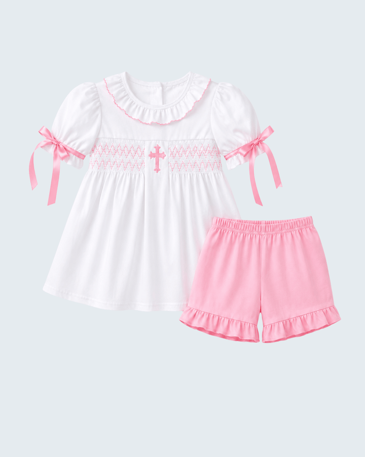 White smocked ruffle shorts set with cross detail; pink bow sleeves and pink ruffled shorts