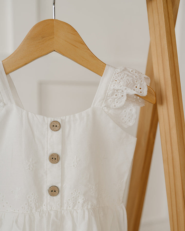 White dress with lace details on a wooden hanger against a white background