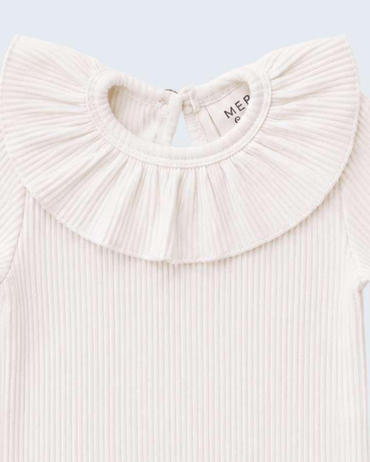 Close-up of a ribbed cream baby top featuring a large pleated ruffled collar, with the brand name &
