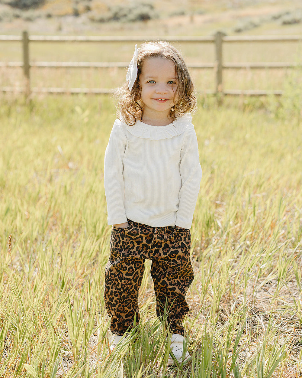 White long-sleeve top with ruffle-trim collar on a child
