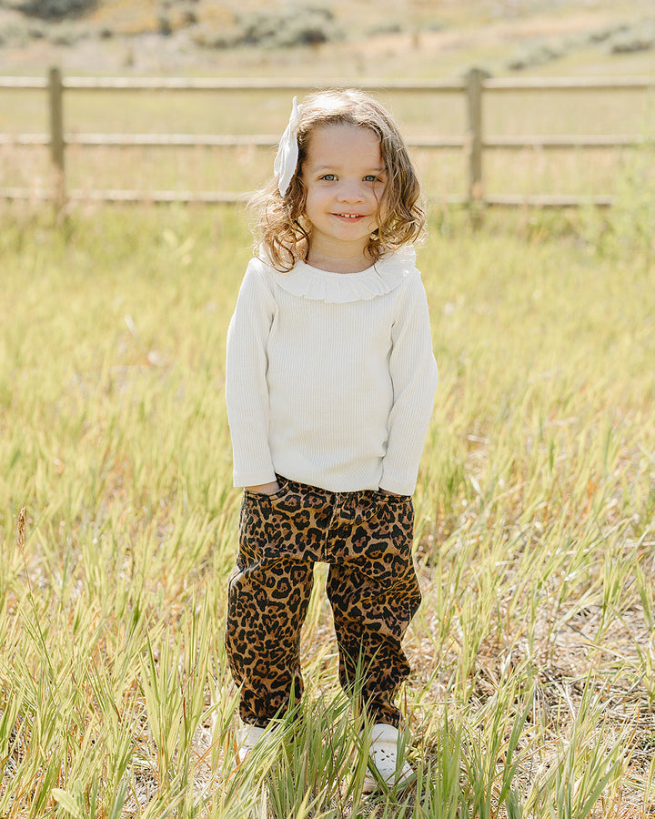 White long-sleeve top with ruffle-trim collar on a child