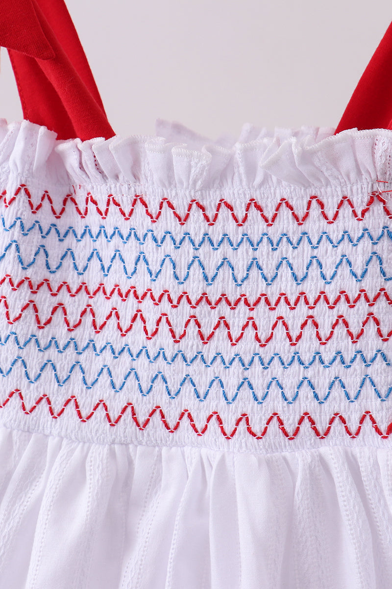 White dress with red and blue embroidery on a white background