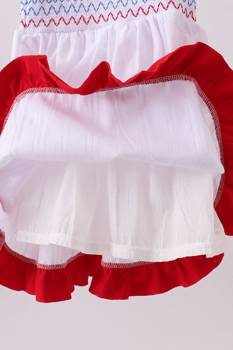 Close-up of a dress with red, white, and blue trim on a light gray background