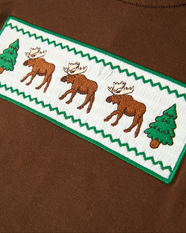 Brown tee chest panel with white fabric stripe, green border, and moose motif
