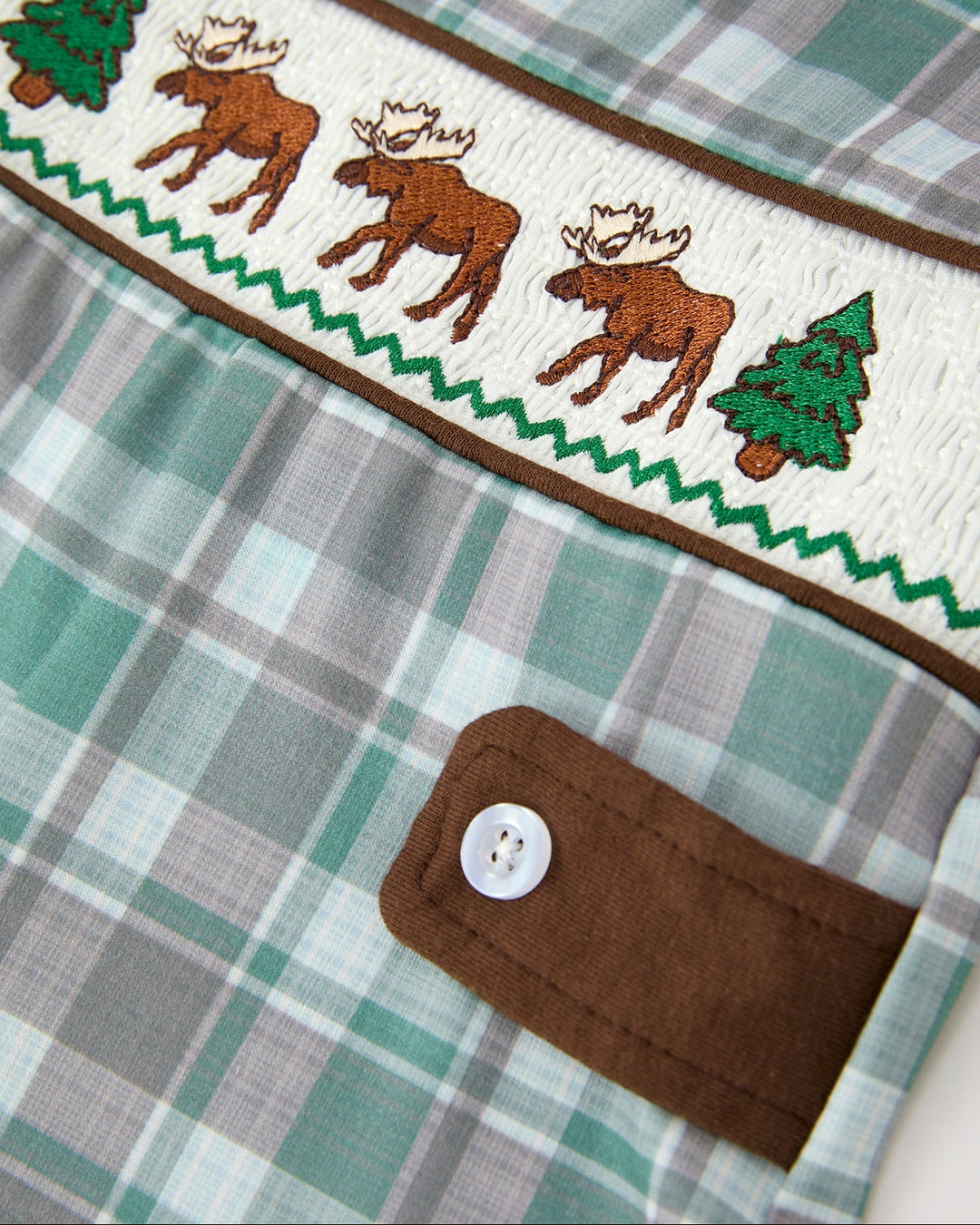 Plaid JonJon bib with embroidered moose and pine trees and a brown button placket