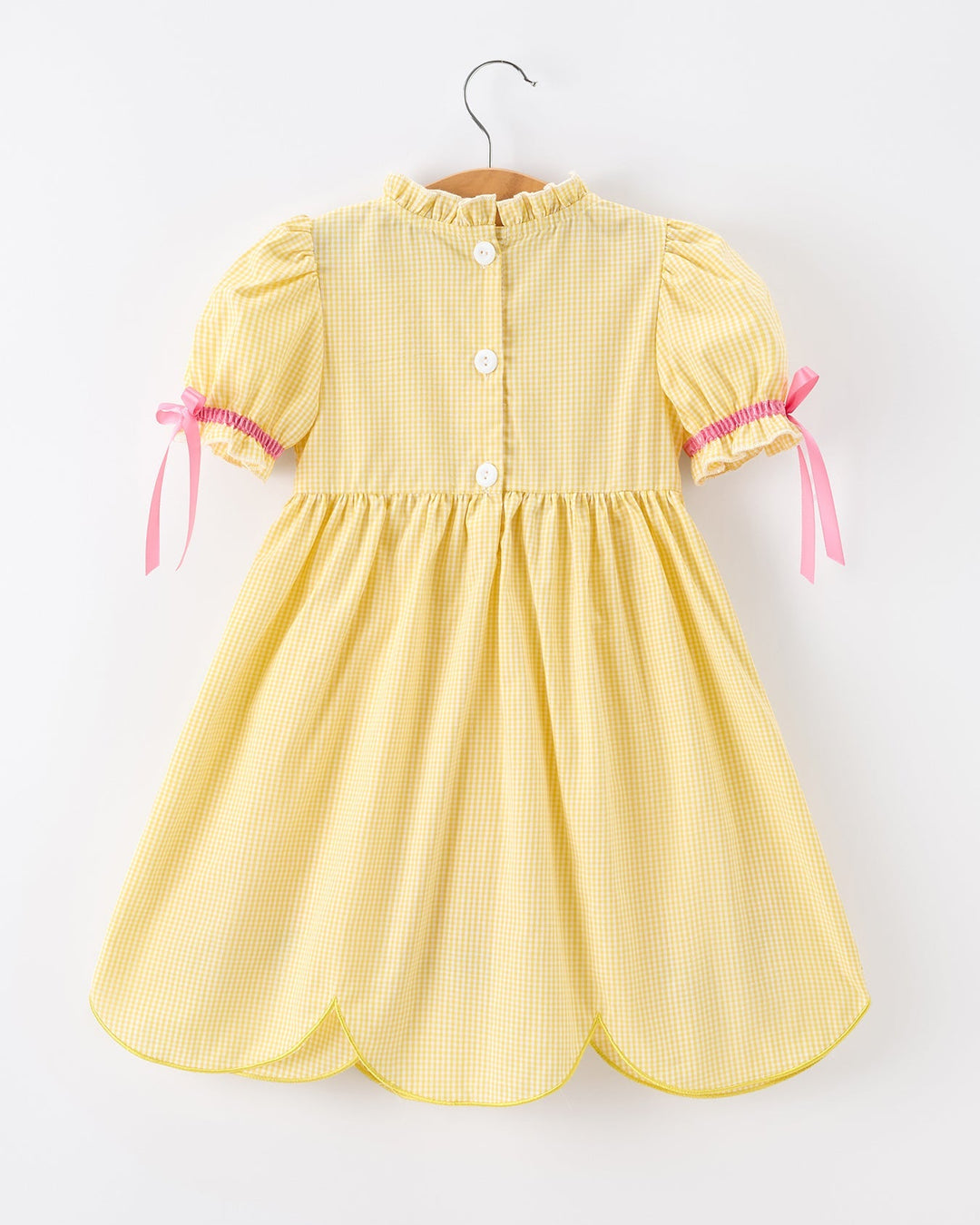 Yellow dress with pink ribbons on a white background