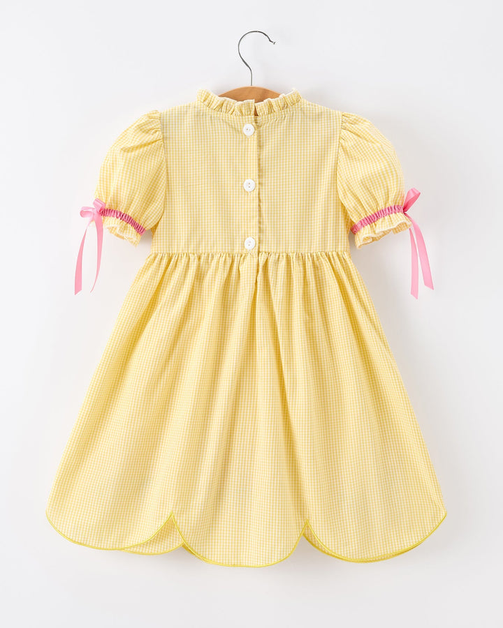 Yellow dress with pink ribbons on a white background