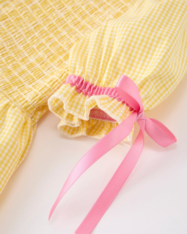 Yellow checkered dress with a pink ribbon on a light background
