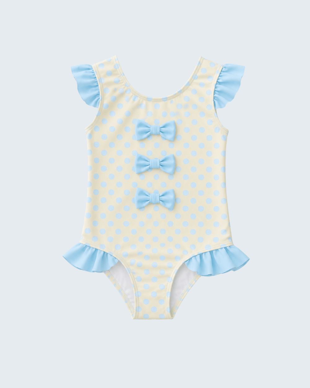 Yellow swimsuit with blue polka dots and ruffles on a light gray background