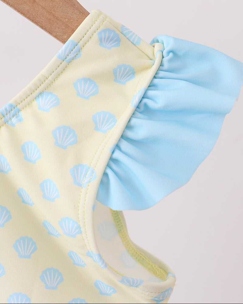 Close-up of a yellow swimsuit with blue shell pattern and ruffled edge on a light background