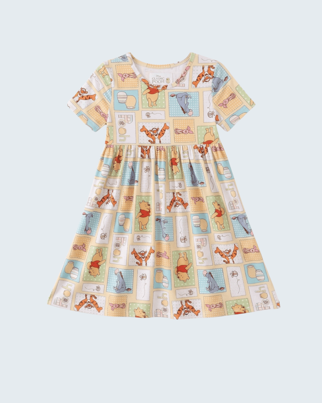 A short-sleeve dress featuring a colorful cartoon animal print on a cream background, displayed against a solid light gray background.